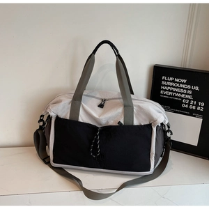 Detail of the cream and black nylon travel bag with front drawstring pocket and shoulder strap