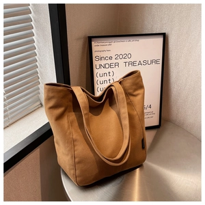 Close-up of caramel canvas tote bag with front pocket on a metallic round table