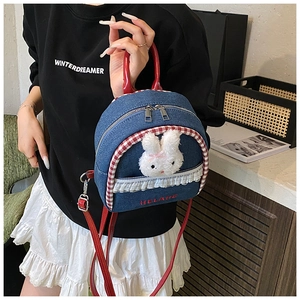 Detailed close-up of blue denim backpack with plush bunny and red lace trim