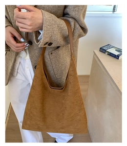 Detail view of the brown suede tote bag with flat leather shoulder strap on a model