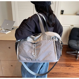 Detail view of large travel bag with nylon texture, front drawstring pocket and shoulder strap