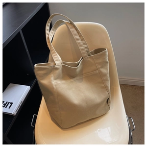 Detail of beige canvas tote bag with front pocket showing thick textured material