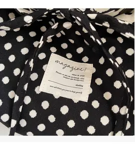 Detailed view of black fabric tote bag with white polka dots and a sewn-on textile label