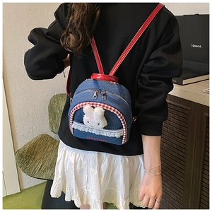 Detail of denim backpack with cute plush rabbit, red straps and lace trimming
