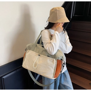 Close-up of sage green and beige tricolor travel bag with functional front drawstring pocket