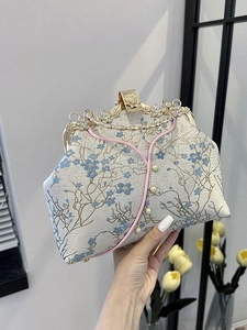Vintage cheongsam clutch bag with blue floral jacquard and pearl accents held by hand