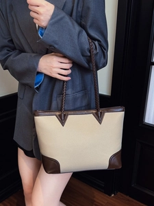 Fashionable beige and brown patchwork tote bag with woven strap on office suit model