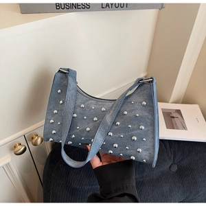 Détail du sac sous l'aisselle en denim bleu clair avec des clous argentés ronds