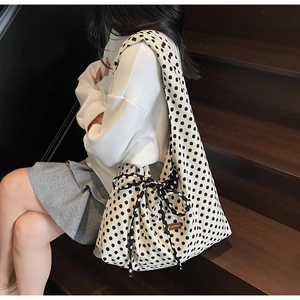 Close-up of beige canvas polka dot tote bag featuring a decorative bow on the strap