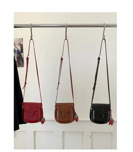 Detailed display of three vintage saddle bags in burgundy, brown and black with strawberry charms