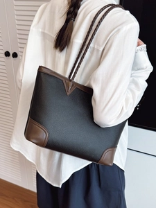 Fashionable two-tone oversized tote bag in black and brown leather worn by a model