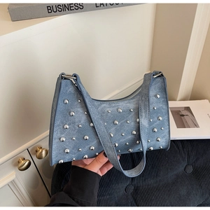 Détail des rivets argentés sur sac à bandoulière en denim bleu avec sangle large