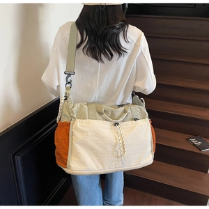Detail of expandable travel bag showing color-block design and adjustable drawstring pocket