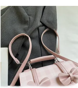 Dettaglio borsa rosa a quadri con fiocchi, manico rotondo e tracolla lunga rimovibile