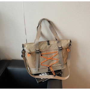 Détail du sac de voyage multifonction avec cordons orange posé sur un canapé noir