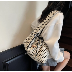 Detail of beige canvas tote bag with black polka dots featuring side drawstring bow