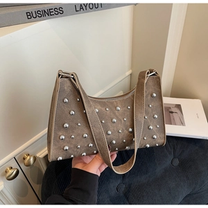Détail du sac à bandoulière marron vintage avec rivets métalliques et boucles argentées