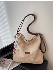 Chic beige tote bag with brown straps and hippo pendant on a stylish work desk