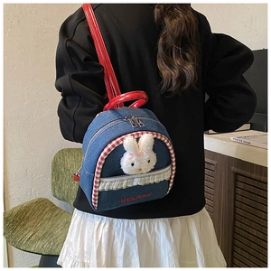 Detail of blue denim backpack with red handles and cute plush bunny decoration