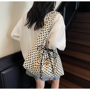 Close-up of polka dot canvas tote featuring a side ribbon bow and leather label detail