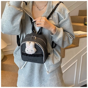 Close-up of denim mini backpack with plush rabbit embroidery and ruffled lace detail
