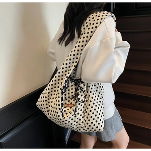 Detailed back view of a large white polka dot canvas tote bag worn by a model