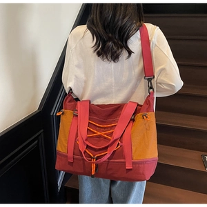 Détail du sac de voyage rouge et orange avec passant pour valise et cordon croisé