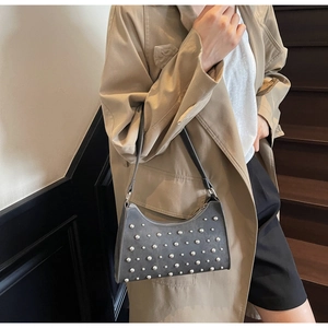 Détail d'un sac porté épaule gris foncé avec rivets argentés et bandoulière en cuir