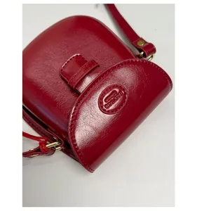Detailed view of red leather saddle bag with embossed logo and gold hardware