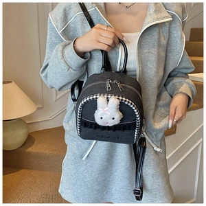 Detail of grey denim mini backpack featuring a plush rabbit and embossed HELAHE logo