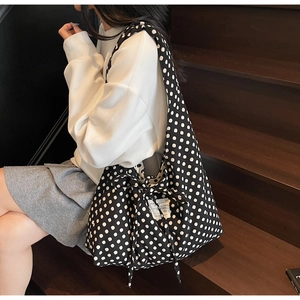 Detailed view of polka dot canvas tote bag with drawstring closure on wooden stairs