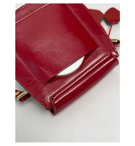 Close-up of red glossy leather bag featuring a functional anti-theft back pocket and gold hardware