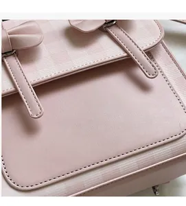 Dettaglio borsa in pelle sintetica rosa con decoro a fiocco e patta a motivo a quadri