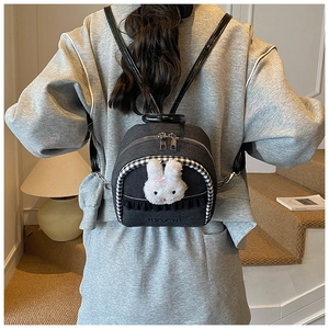 Detail view of mini denim backpack with 3D plush rabbit decor and ruffle edge on a model