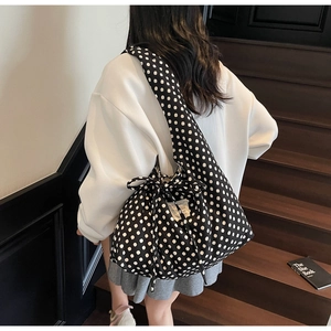 Polka dot canvas tote bag with drawstring closure and wide strap on casual white hoodie