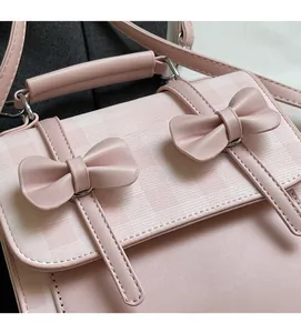 Dettaglio dei fiocchi rosa e del motivo a scacchi sulla borsa a mano in pelle da donna