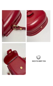 Close-up of red leather saddle bag with golden magnetic buckle and precise stitching