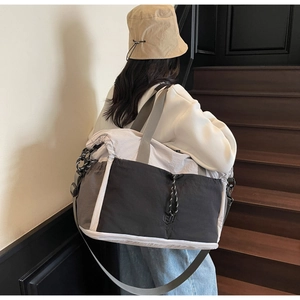 Detail of a large color-block travel bag featuring grey tones and adjustable drawstring