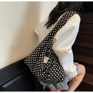Detail of a large polka dot tote bag with a woven brand label for daily commute style