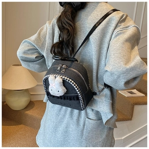 Close-up of denim backpack featuring a plush bunny charm and black lace trim detail