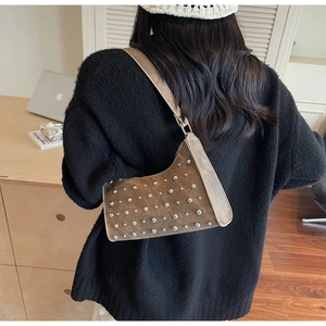 Gros plan d'un sac hobo marron vintage avec clous argentés porté sur l'épaule