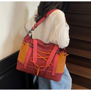Détail du sac de voyage bicolore avec cordons élastiques frontaux sur des escaliers