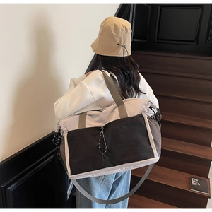 Detailed view of spacious travel bag with contrast panels and drawstring on wooden stairs