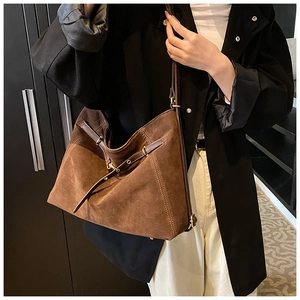 Detail of brown suede tote bag featuring fine stitching and gold buckle hardware