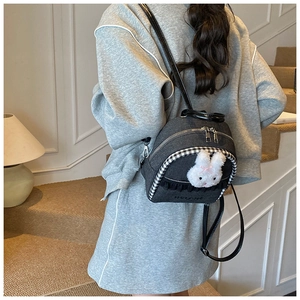 Detail of dark gray denim mini backpack featuring a plush bunny and lace trim decoration