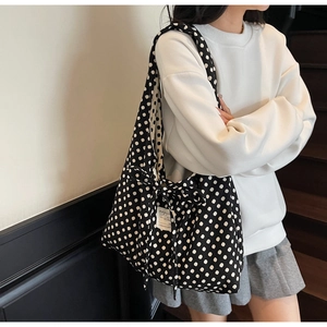 Detailed close-up of oversized black polka dot canvas tote with a large side bow decoration
