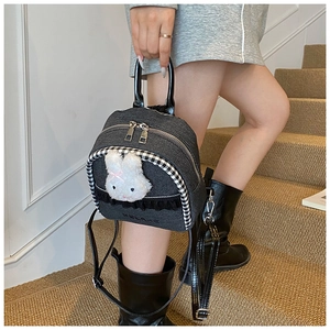 Detail of gray denim backpack with 3D bunny plush and checkerboard piping texture