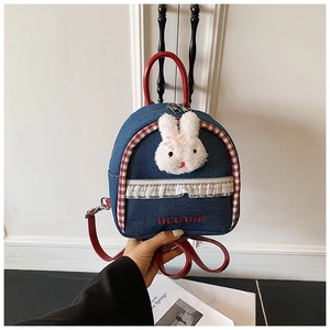 Close-up of denim backpack featuring plush rabbit, lace trim and red leather handle