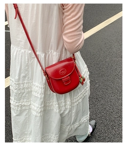 Detail view of red saddle crossbody bag featuring unique strawberry charms and sleek leather