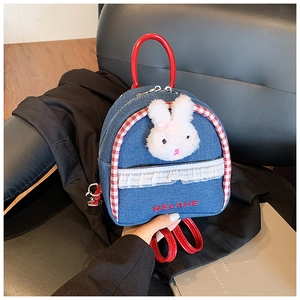 Detail view of mini denim backpack featuring lace trim and cute plush bunny patch